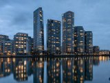 Waterfront high rise buildings at blue hour reflected in still water. (AI generated image)